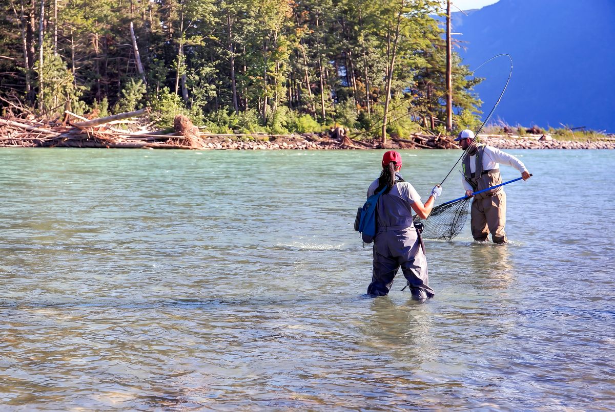 Guide netting fish in river with angler