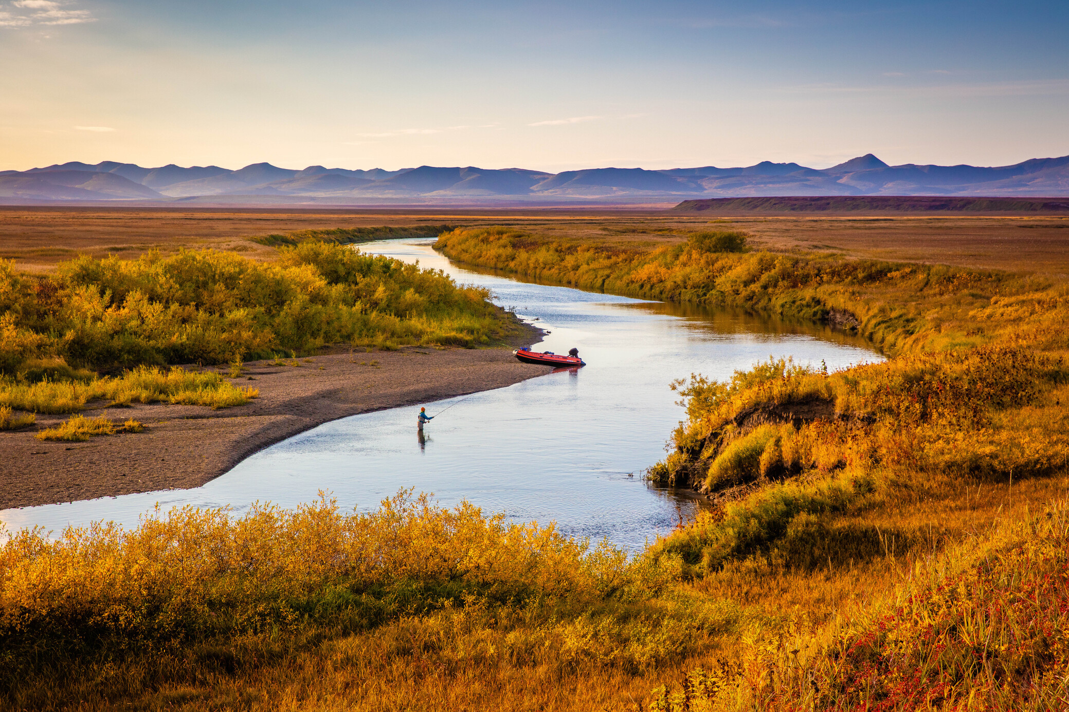 A fly angler casting on a wide Kamchatka steelhead river